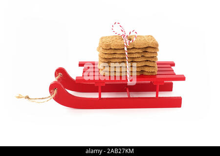 Spekulatius, Speculaas, Speculoos, spiced Christmas cookies on red wooden sledge isolated on white. Low Angle view. Stock Photo