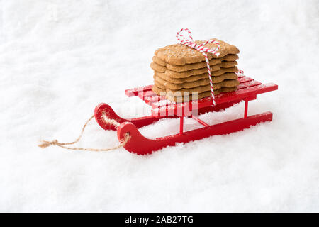 Spiced Christmas cookies called Spekulatius, Speculaas, Speculoos, in Germany, Netherlands and France, on red wooden sledge in snow. Stock Photo