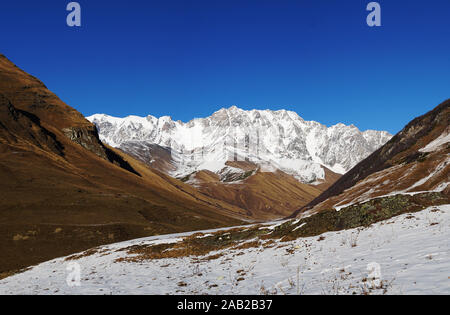 Mountain landscape panorama. Majestic mountain peaks covered with snow against a bright blue sky. Stock Photo