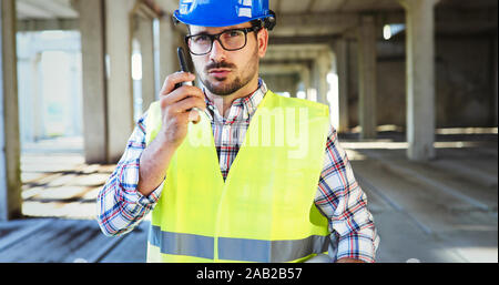 Male architect with blueprints using walkie-talkie Stock Photo
