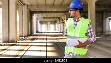 Male architect with blueprints using walkie-talkie Stock Photo
