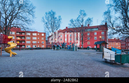 Playground in centre of square surrounded by colourfully painted apartment blocks at dawn, Vasastaden, Stockholm, Sweden Stock Photo
