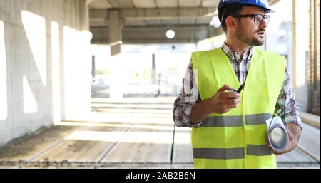 Architect holding rolled up blueprints at construction site Stock Photo