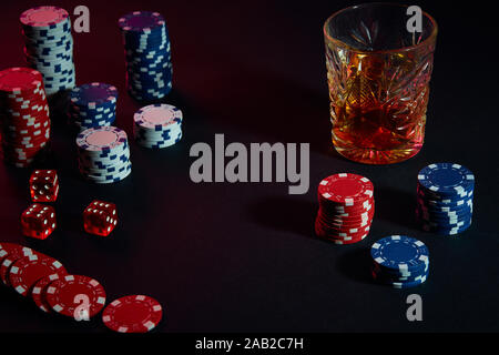 Poker chips and wine glass of cognac on dark table. Gambling Stock Photo