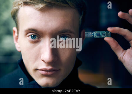 man holds a flash drive near his head. modern technology memory concept Stock Photo