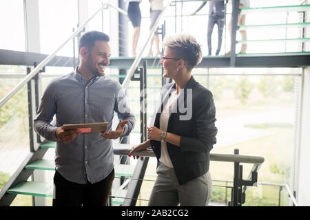 Business people discussing over documents in office lobby. Stock Photo
