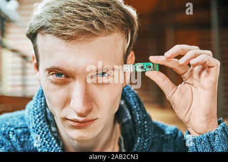 man holds a flash drive near his head. modern technology memory concept Stock Photo