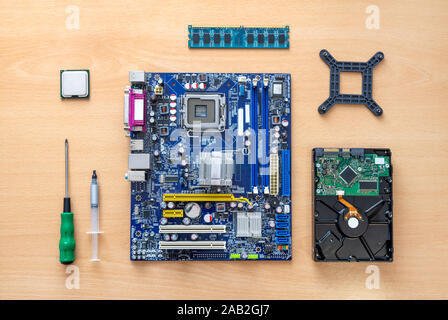 Motherboard, processor, memory, hard drive, screwdriver and thermal paste on the table. The concept of assembling computer. Top view, flat lay. Stock Photo