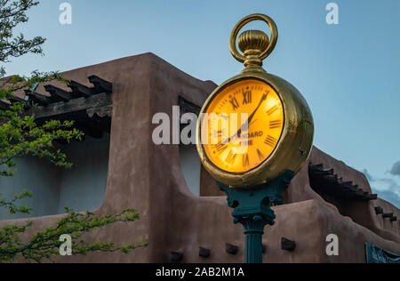 Gold pocket watch, vintage street clock standard time text in Santa Fe city center, traditional building and blue sky at sunset background, New Mexico Stock Photo