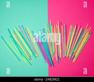 stack of multi-colored plastic tubes for a cocktail on a multi-colored background,  concept of environmental pollution by objects that decay in the gr Stock Photo