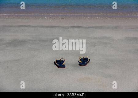 Black flip-flop on a sandy ocean beach,Summer holiday and vacation concept. Stock Photo