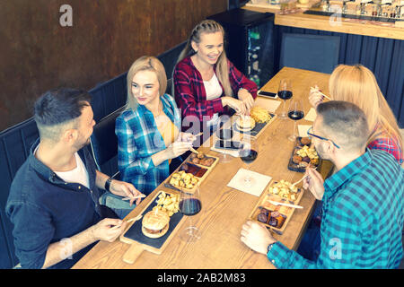Group of young best friends having fun at trendy pub eating hamburgers Stock Photo