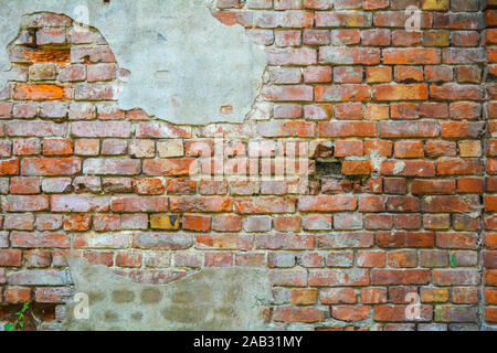 Old ruined orange brick wall with concrete remains and cracks. Damaged antique brick wall texture Stock Photo