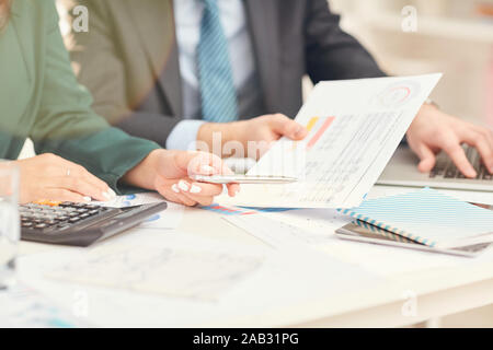 Close up of unrecognizable businessmen pointing at documents during business meeting in office, copy space Stock Photo
