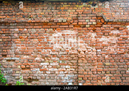 Old ruined orange brick wall with concrete remains and cracks. Damaged antique brick wall texture Stock Photo