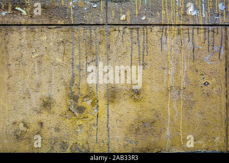 Texture of old yellow stucco wall of urban building with drips of yellow, brown and white paint and dirt. Old plaster with paint leak Stock Photo