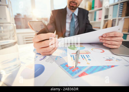 Closeup of unrecognizable businessman analyzing statistics reports while sitting at desk in office, copy space Stock Photo