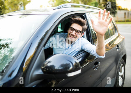 selective focus of happy man driving car and waving hand