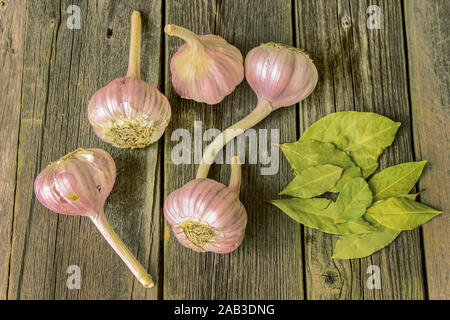 Garlic heads and dried laurel leaves on a wooden table Stock Photo