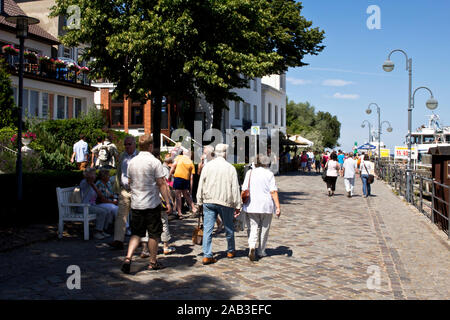 Touristen flanieren über die Promenade im Hafen von Warnemünde und genießen das sommerliche Wetter |Tourists stroll along the boardwalk at the port of Stock Photo