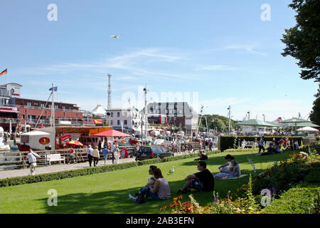 Touristen genießen das sommerliche Wetter auf der Promenade im Hafen von Warnemünde |Tourists enjoy the summer weather on the boardwalk at the port of Stock Photo