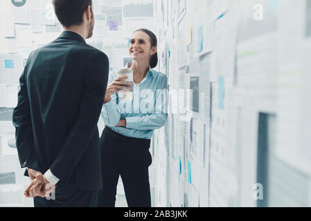 Happy business colleagues having a coffee break together and flirting, relationships concepts Stock Photo