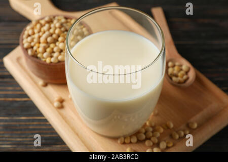 Glass of soy milk and soybeans seeds on wooden background, space for text. Closeup Stock Photo