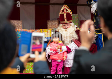 Eindhoven, The Netherlands, November 23rd 2019. Sinterklaas wearing his costume and having  a little girl next to him while posing for the camera and Stock Photo