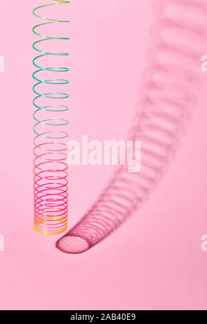 Vertical stretching plastic slinky toy with curved shadow. Stock Photo