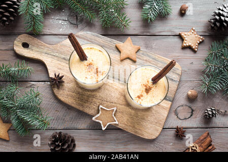 Eggnog Christmas drink with grated nutmeg and cinnamon sticks for Christmas and winter holidays. Stock Photo