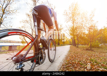 Young triathlete cyclist riding bike in autumn park. Wide angle view with copy space