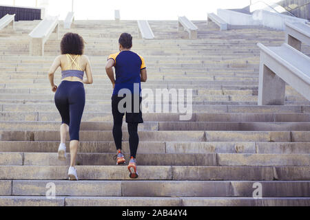 young woman and man running upstairs on city stairs, fitness, urban sports workout and healthy lifestyle concept, copy space for text Stock Photo