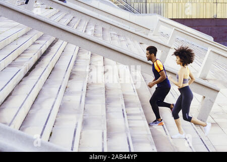 young latin woman and afro american sports man training running up stairs in the city. fitness, urban sports workout and healthy lifestyle concept, co Stock Photo