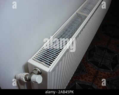 White metal heating radiator mounted on a wall in room interior.  Bucharest, Romania, 2019. Stock Photo
