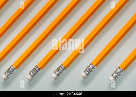 Background with a pattern consisting of a closeup of a row of orange lead pencils with white rubbers on the end lying on a white glass plate.