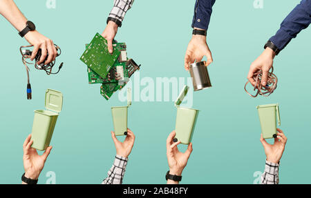 Four hands hold electrical waste and garbage containers on empty blue background. Ecological concept of recycling garbage Stock Photo