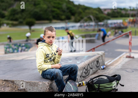 A cute little boy with ADHD, autism, Asperger syndrome riding around the skatepark, chilling and having fun while exercising and releasing energy Stock Photo