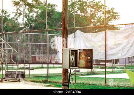 Old rusty electrical power control box on rusted electric pole in the public park. Stock Photo