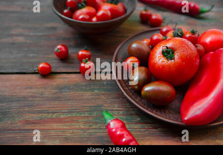 Fresh small tomatoes and spicy pepper in plate on kitchen Stock Photo