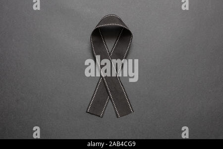 Melanoma awareness ribbon on black color background. Mourning and ...