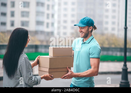 Bearded delivery man smiling while talking to customer Stock Photo