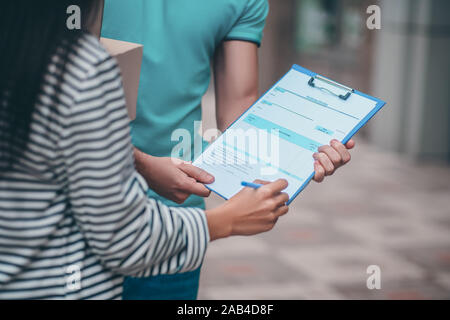 Close up of client signing declaration after receiving parcel Stock Photo