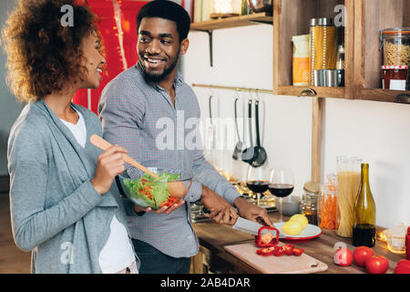 Young african-american couple preparing salad in kitchen Stock Photo