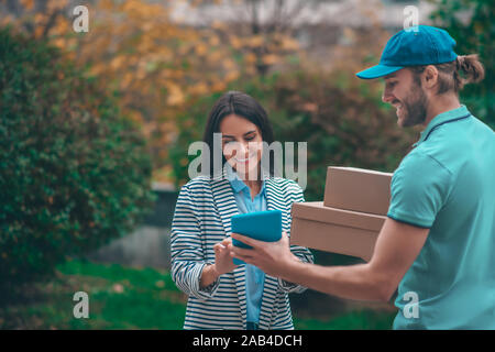Delivery man holding tablet while standing near client Stock Photo
