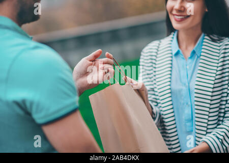 Woman smiling while talking to delivery man and taking her bag Stock Photo