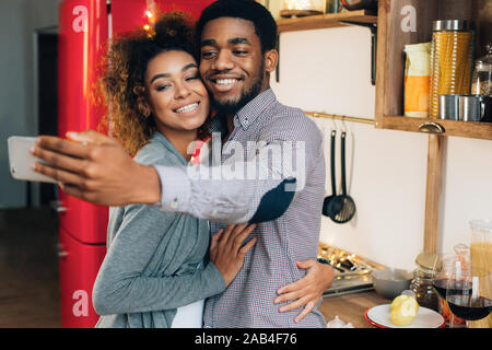 Black girl making selfie with her cooking boyfriend Stock Photo