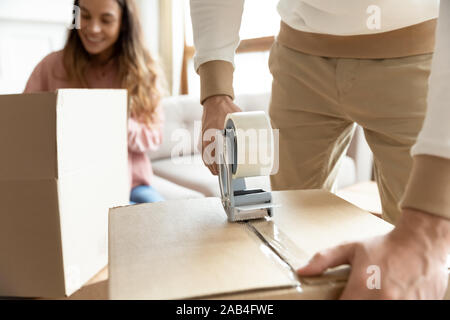 Man holding tape dispenser packing cardboard box on moving day Stock Photo