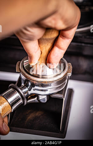 Barista presses ground coffee using tamper. Stock Photo