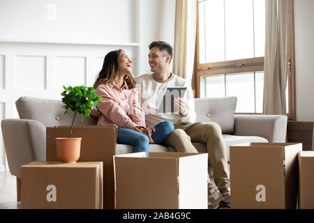 Smiling couple talking using tablet computer on moving relocation day Stock Photo