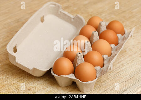 Brown chicken eggs in opened carton box on wooden table Stock Photo